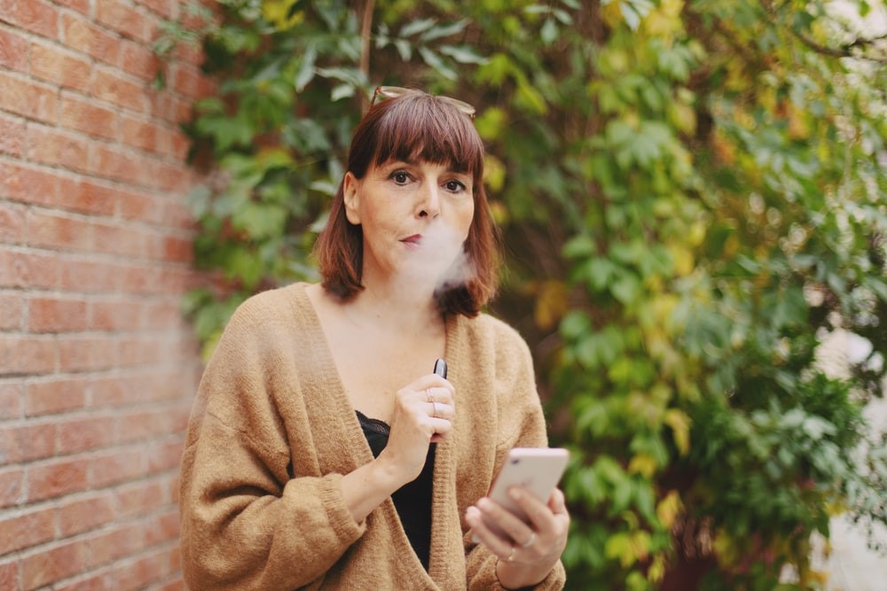 A middle-aged woman vaping outdoors